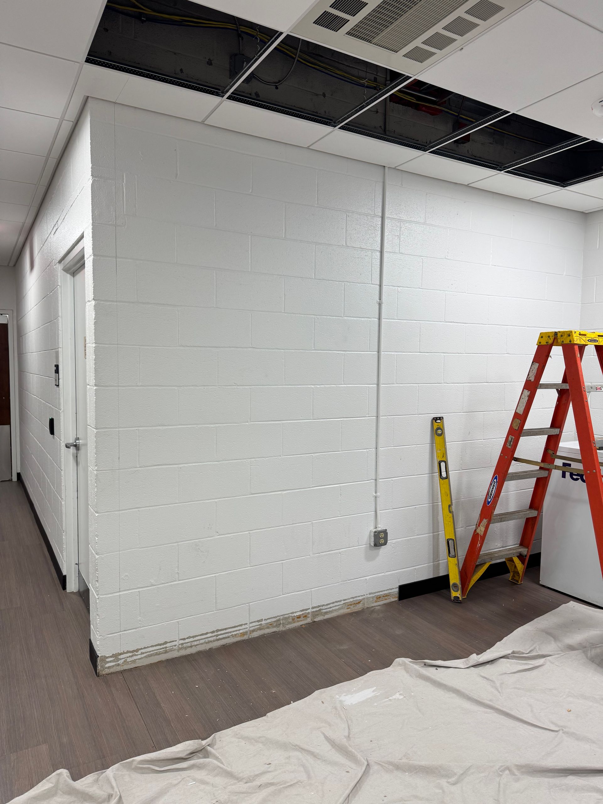 A room with a ladder and a level on the floor