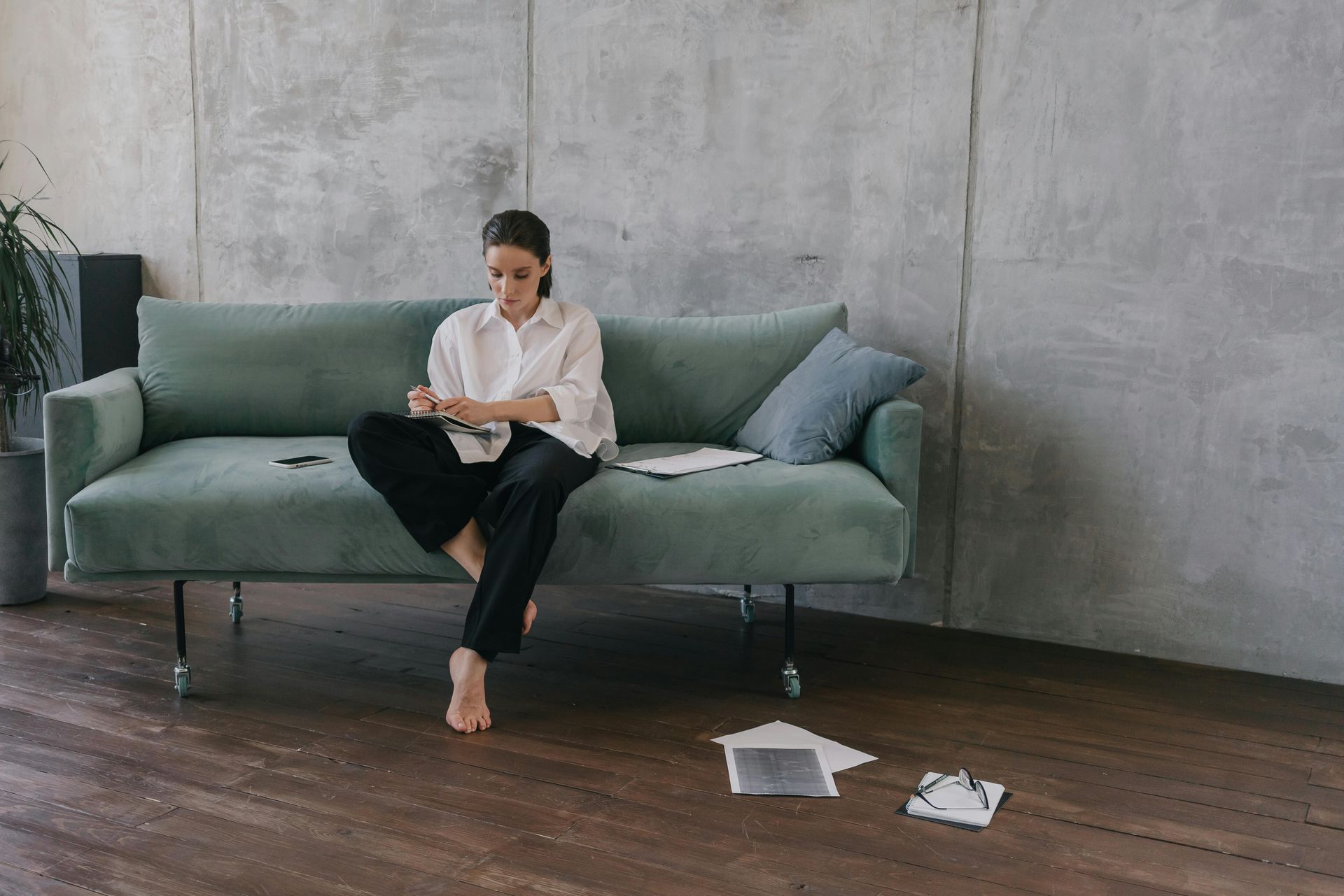 A woman is sitting on a couch looking at her phone.