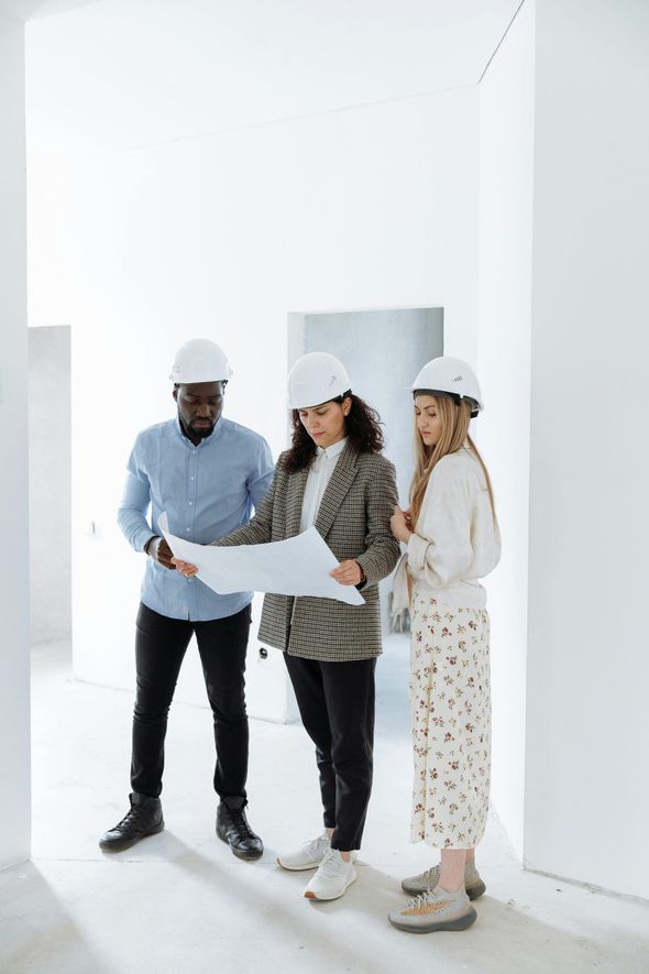 A man and a woman are looking at a blueprint of a room being renovated in in office building.