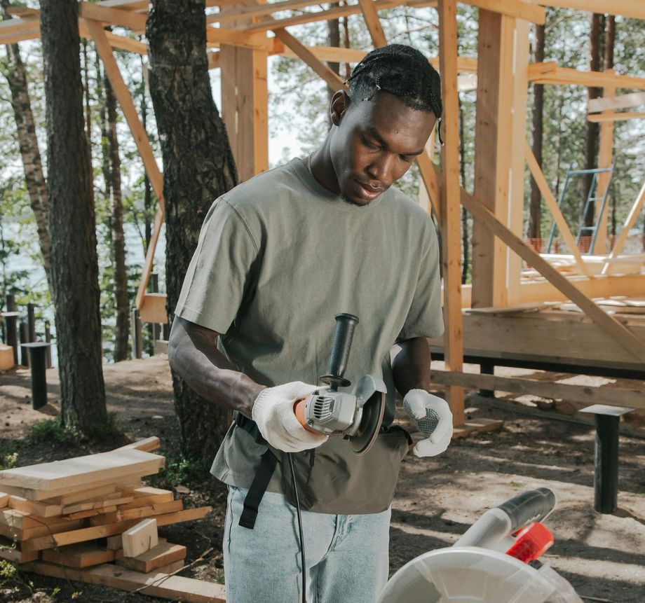 A man is using a carpentry tool on a piece of wood at a construction site