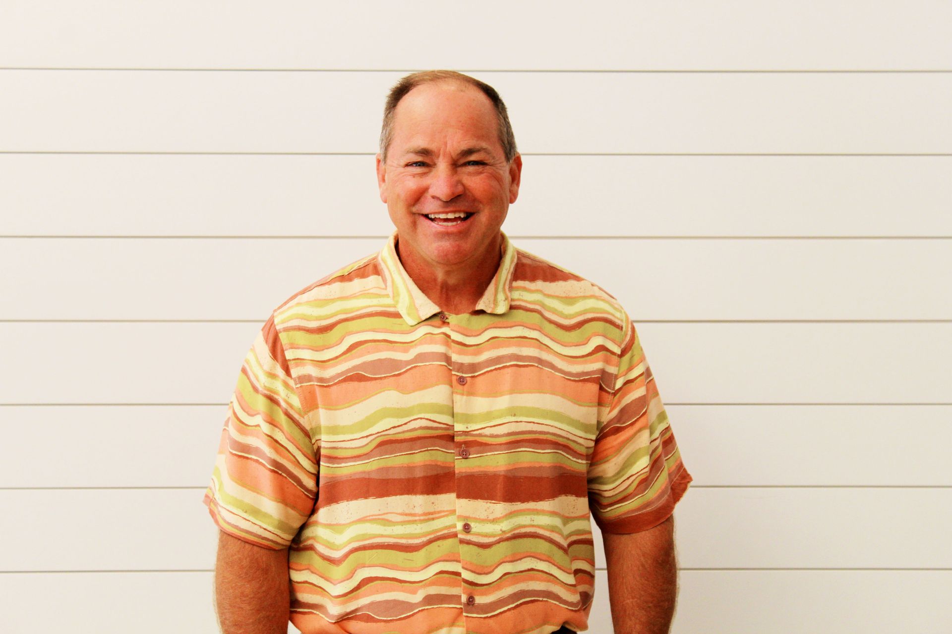 A man in a plaid shirt is smiling for the camera.