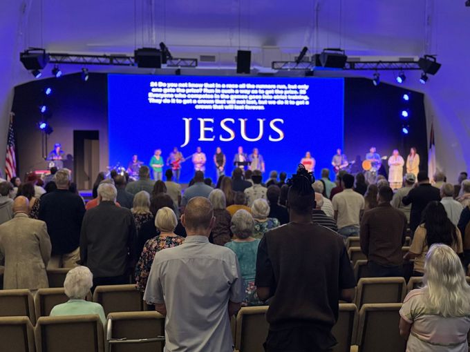 A large group of people are sitting in a church auditorium.