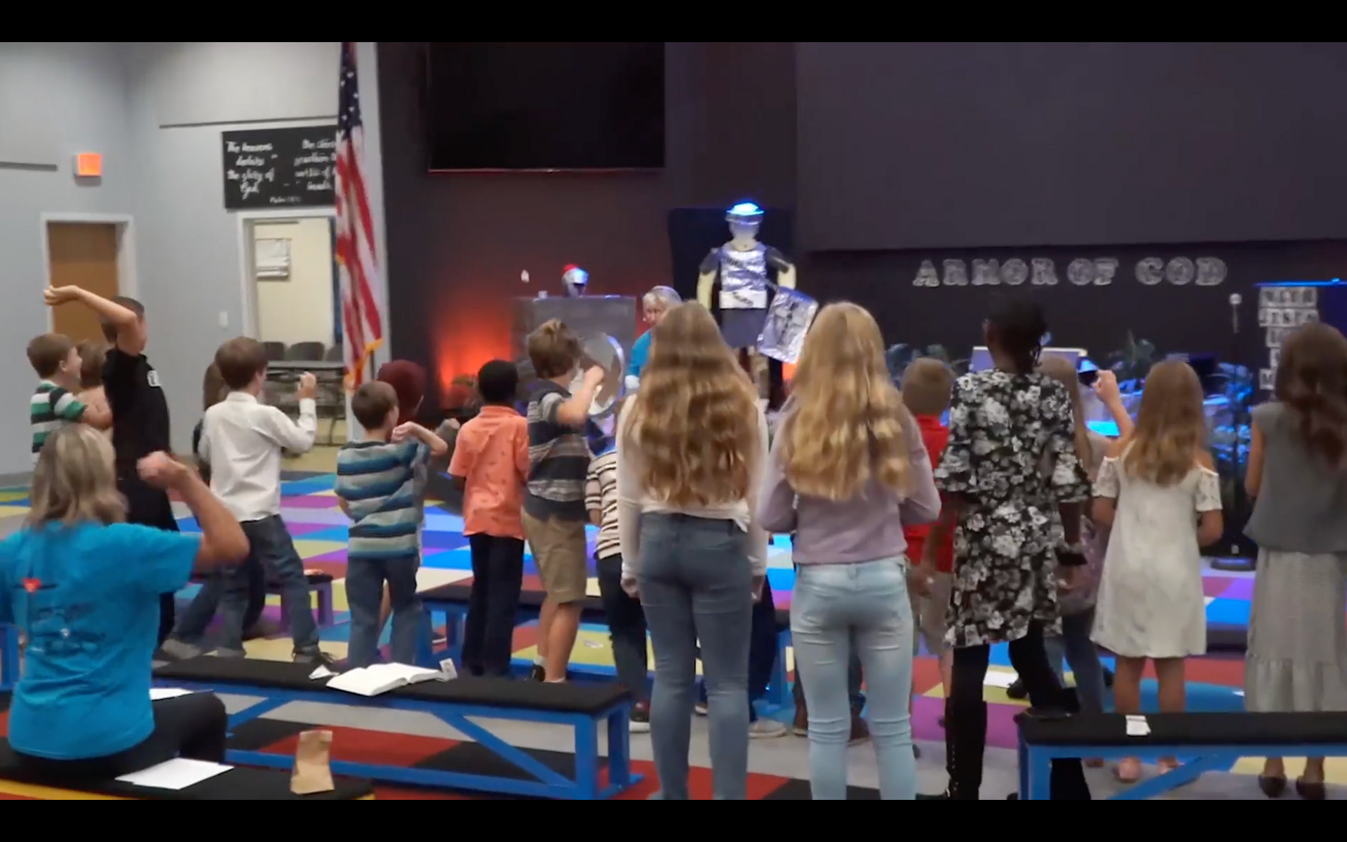 a group of children are sitting on a couch with their hands in the air
