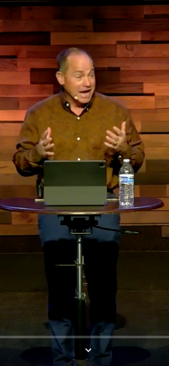 A man is sitting at a table with a tablet and a bottle of water.