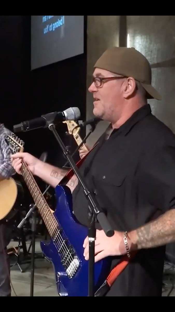 A man singing into a microphone while holding a guitar