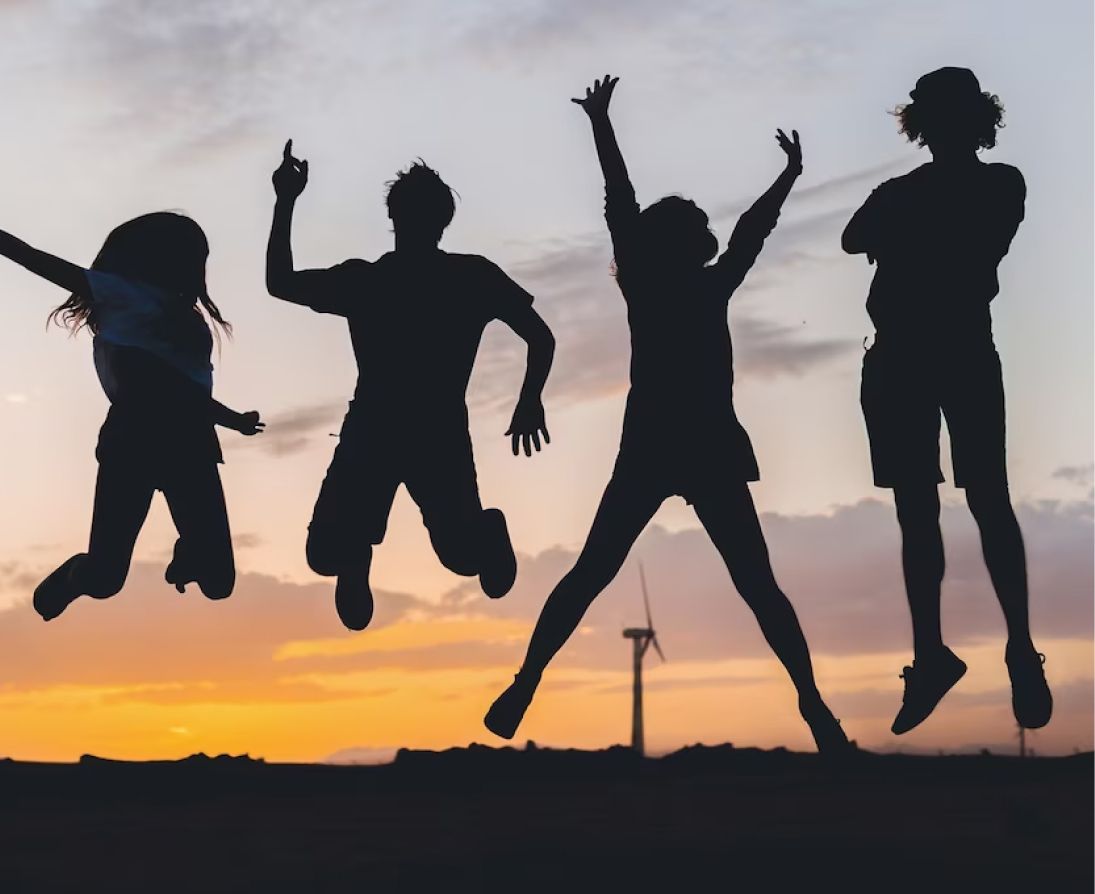 Silhouettes of people jumping in the air at sunset