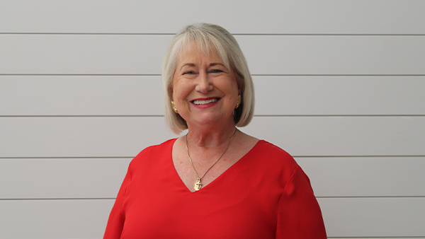 A woman wearing a black shirt and a necklace is smiling.