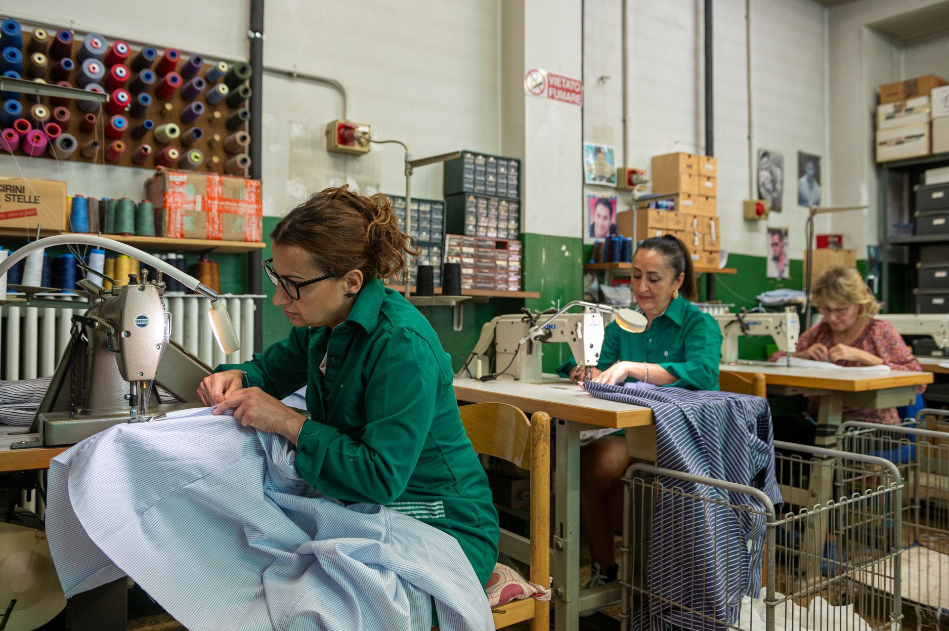 Un gruppo di donne è seduto alle macchine da cucire in una fabbrica.