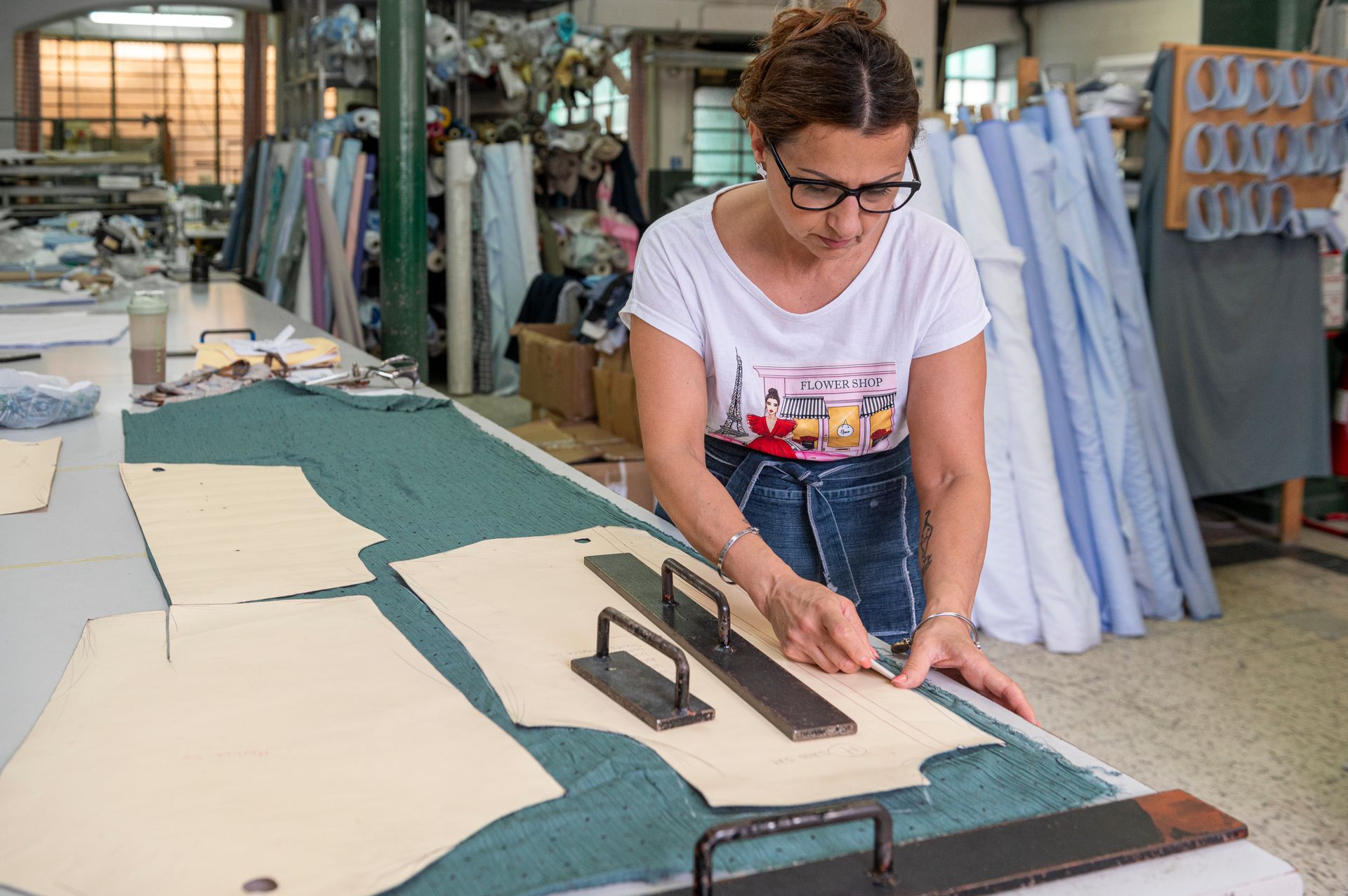 Una donna sta tagliando un modello su un tavolo in una fabbrica.