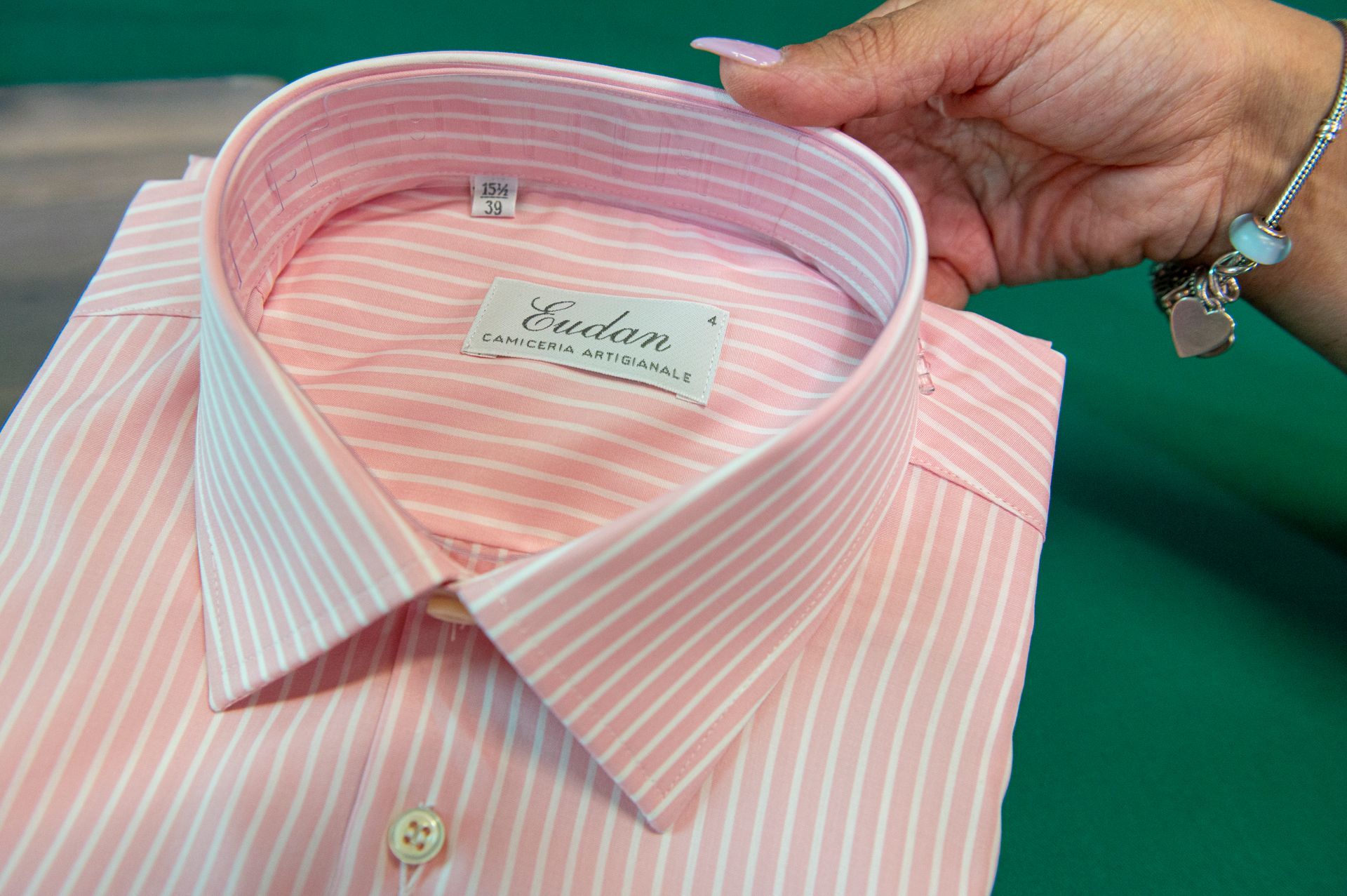 Una donna tiene in mano una maglietta a righe rosa e bianche.