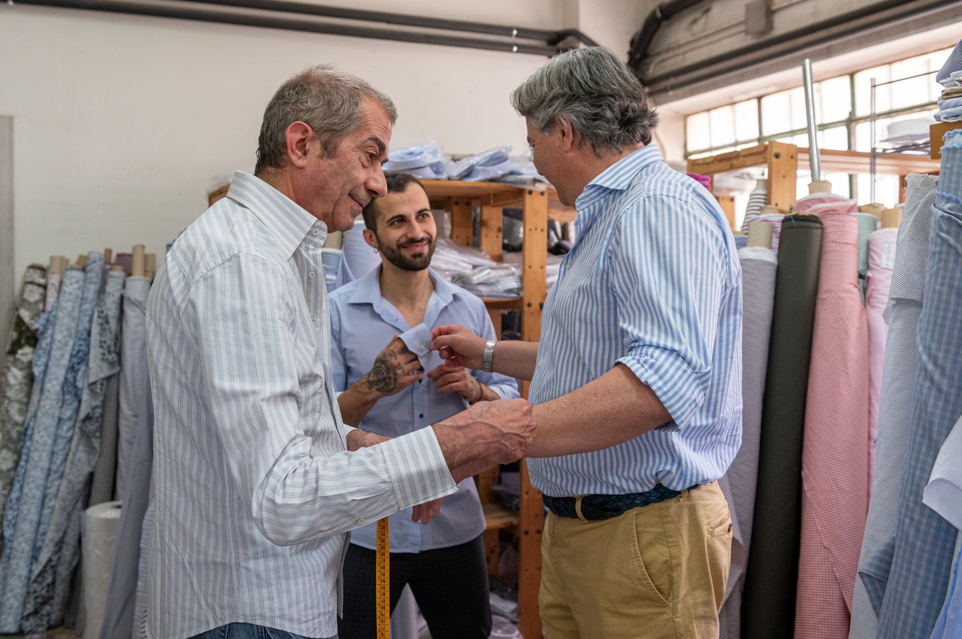 Un gruppo di uomini in una camiceria è in piedi in una stanza e parla tra loro.