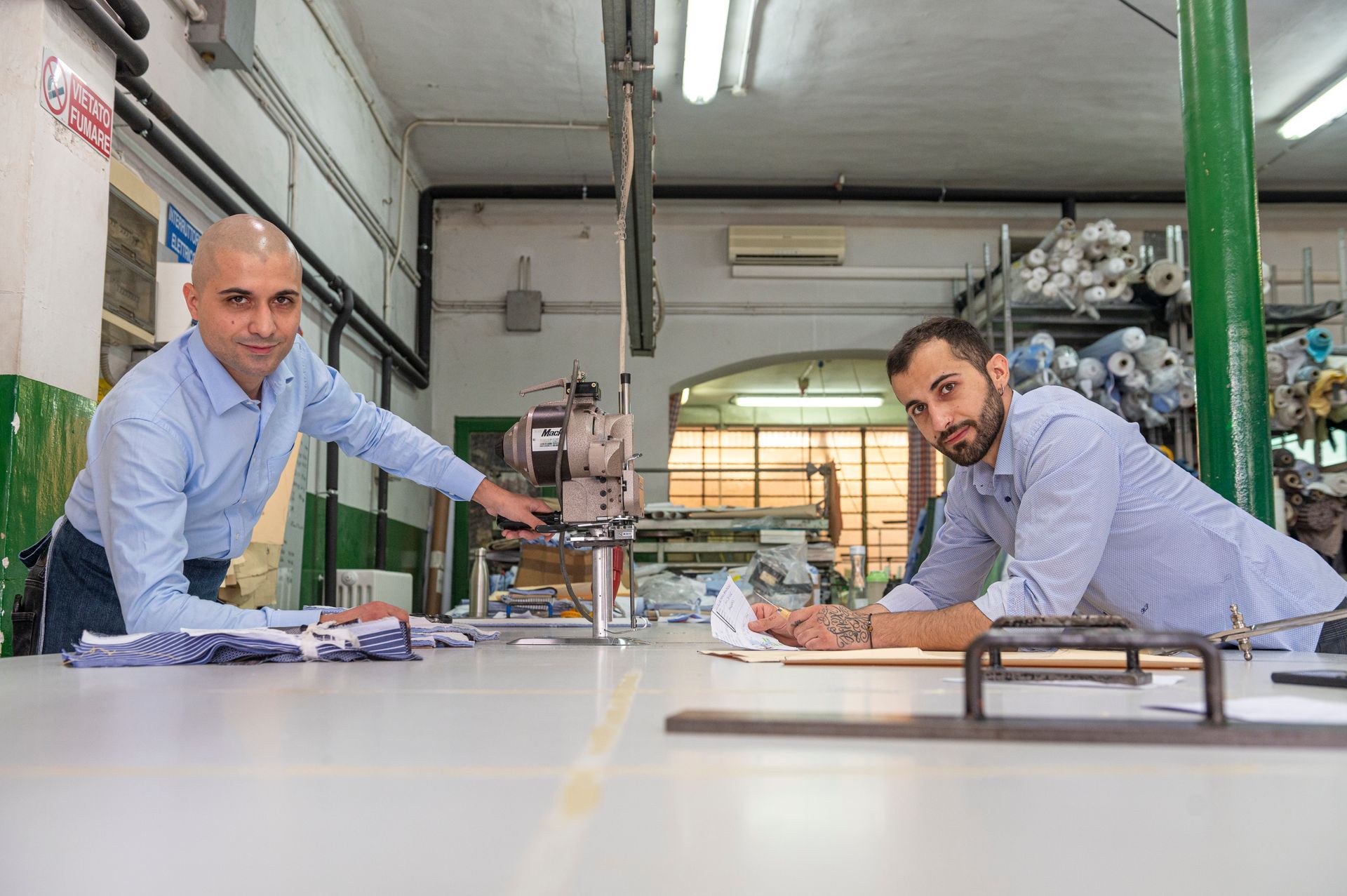Due uomini sono seduti a un tavolo in una fabbrica di camicie