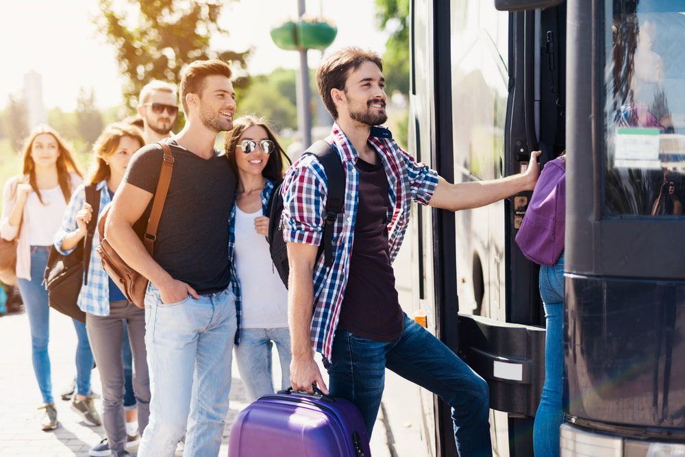 A Group Of People Are Boarding A Bus At A Bus Stop — TJ & B Bus and Coach Pty Ltd In Gold Coast, QLD