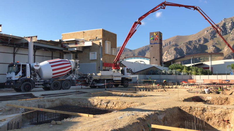 Un camion betoniera sta percorrendo una strada sterrata davanti a un edificio.