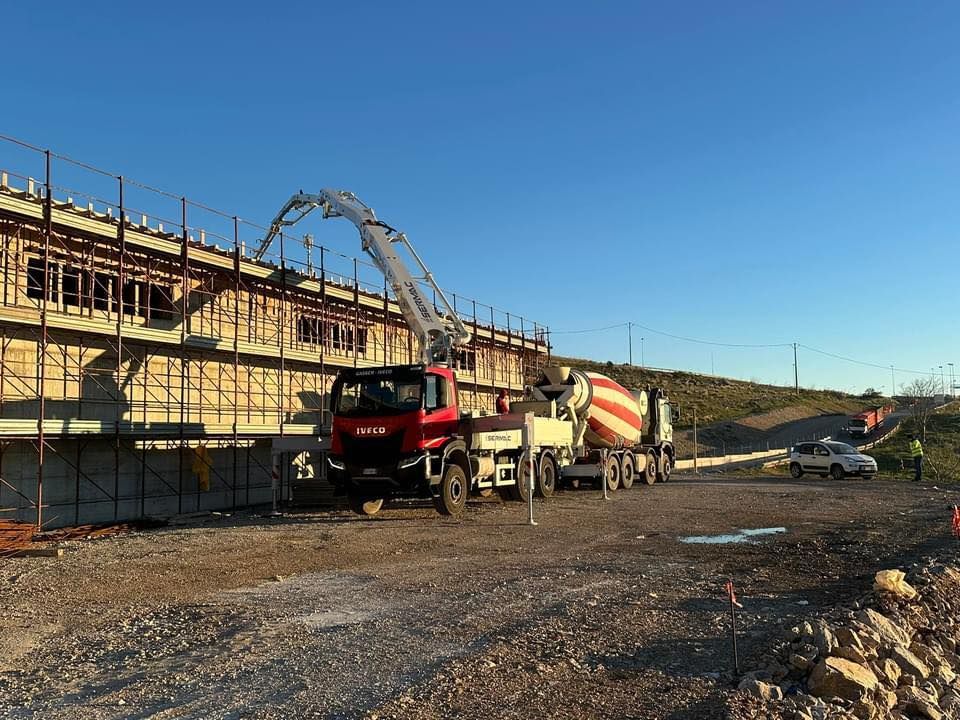 Un'autobetoniera sta pompando calcestruzzo in un cantiere edile.
