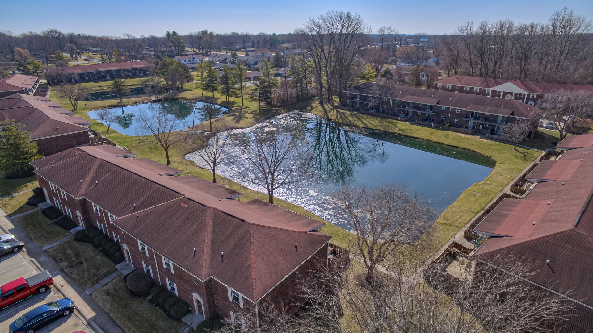 An aerial view of a residential area with a lake surrounded by buildings.