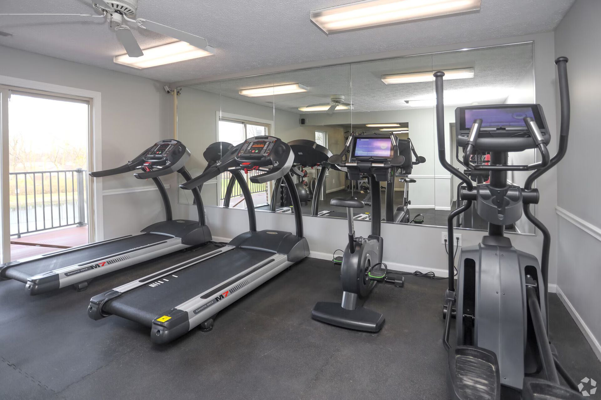 A gym with treadmills , ellipticals and a large mirror.