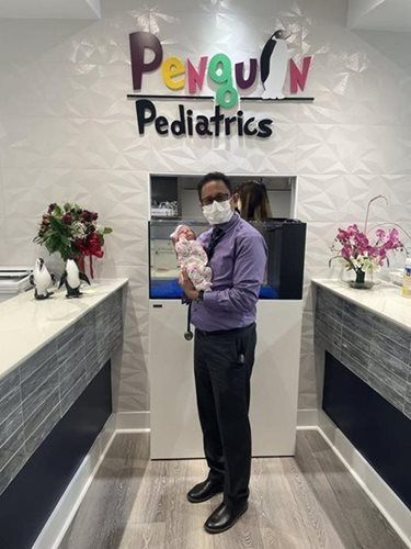 Doctor holding a baby in pediatric office, 