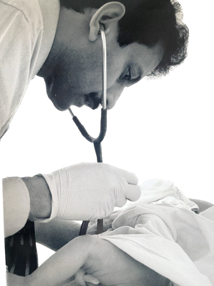 Doctor using stethoscope to examine patient, likely an infant. White coat, gloved hand, close-up shot.