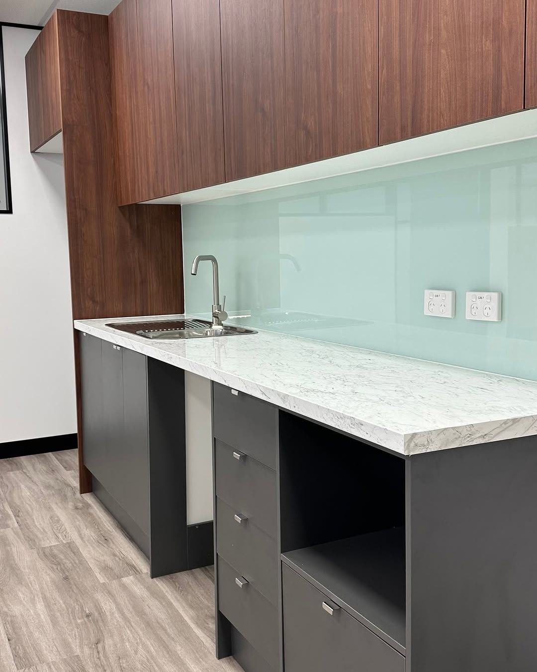 Modern kitchenette with gray cabinets, light countertop, wood upper cabinets, and pale blue backsplash. — Zero 21 Fit-Outs & Joinery: Kitchen Renovation Gold Coast in Robina, QLD