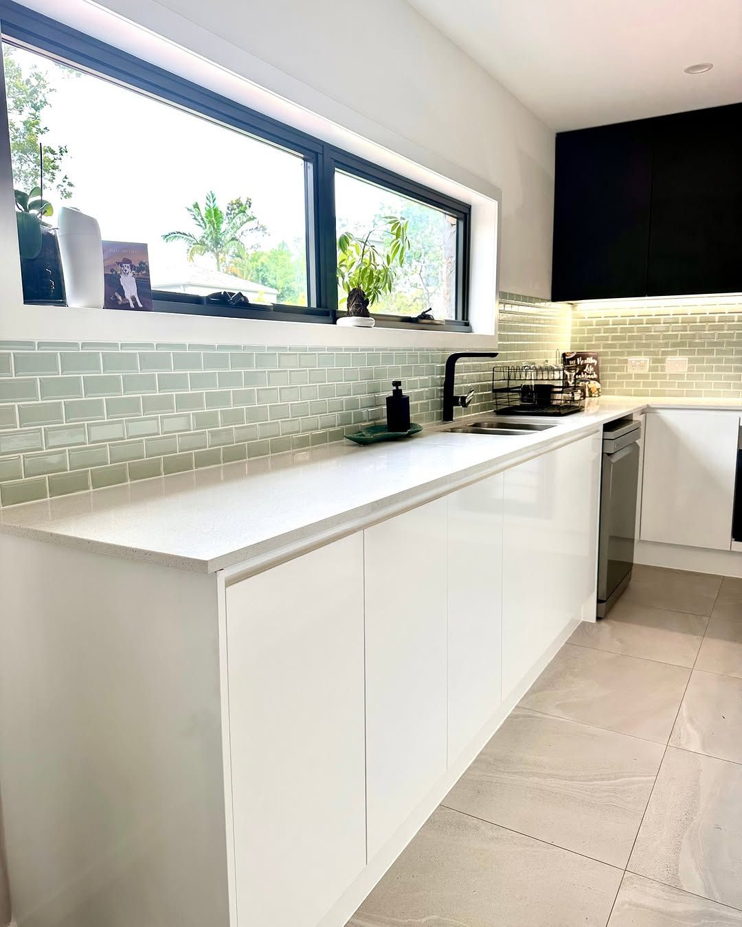 Modern white kitchen with a large window, light blue tile backsplash, and black faucet. — Zero 21 Fit-Outs & Joinery: Kitchen Renovation Gold Coast in Paradise Point, QLD