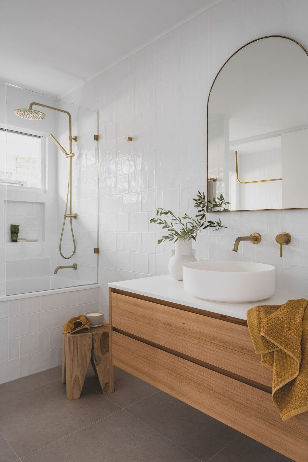 Modern bathroom with white textured tile walls, gold fixtures, wood vanity, and arched mirror. — Zero 21 Fit-Outs & Joinery: Kitchen Renovation Gold Coast in Hope Island, QLD