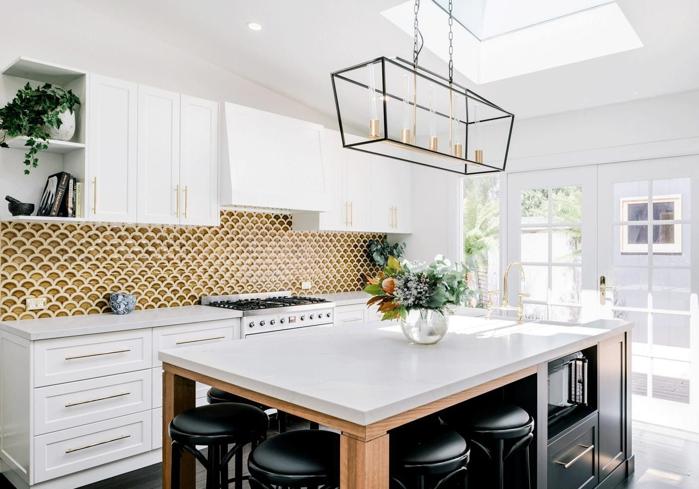 Modern white kitchen with a gold tile backsplash, island, and black stools. — Zero 21 Fit-Outs & Joinery: Kitchen Renovation Gold Coast in Burleigh Heads, QLD