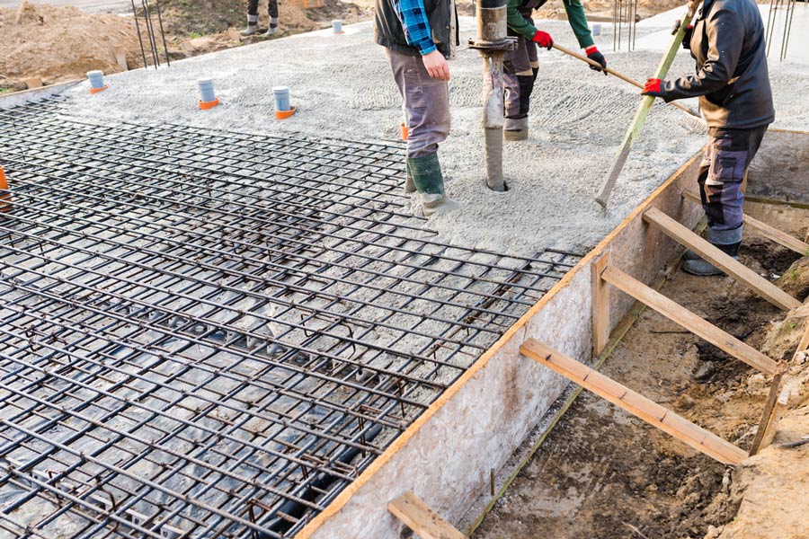 Three Construction Workers Pouring Concrete On The Ground Foundation — Maitland Concreting Specialists In Maitland New South Wales