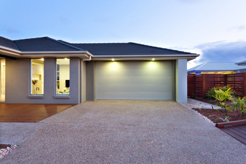 Luxury House Includes A Garage With A White Door And Concrete Driveway — Maitland Concreting Specialists In Singleton NSW