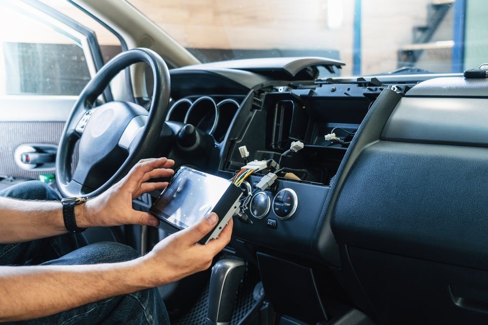 Person Installing Car Radio in a Car Dashboard; Wires Exposed — Mullumbimby Auto Electrical in Ocean Shores, NSW