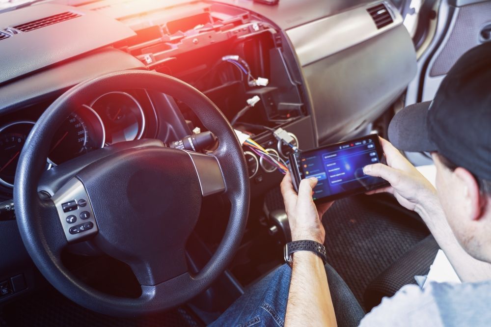 Person Working on Car Dashboard, Using Tablet to Configure the Electronics — Mullumbimby Auto Electrical in Byron Bay, NSW