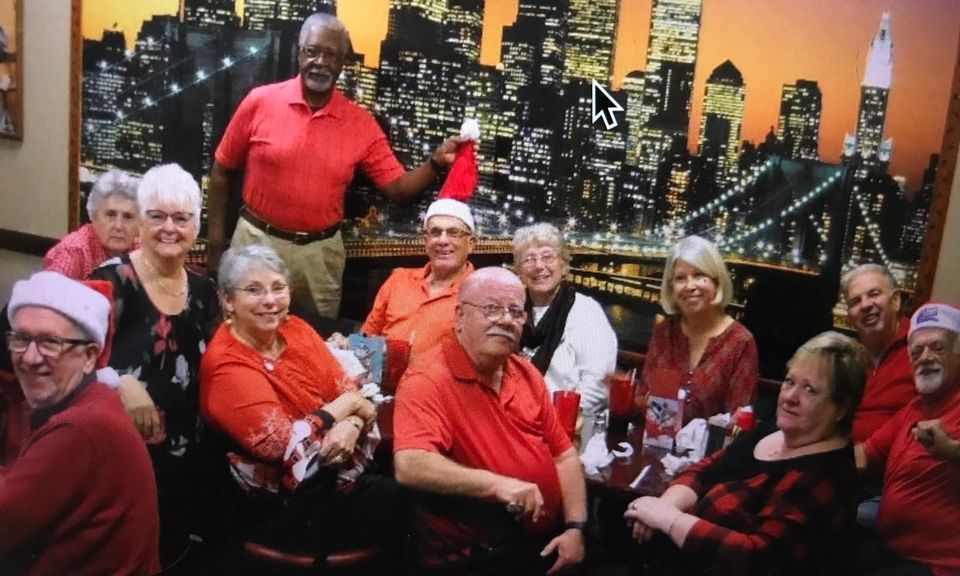 Group of people in red at a holiday gathering. Background of city skyline.
