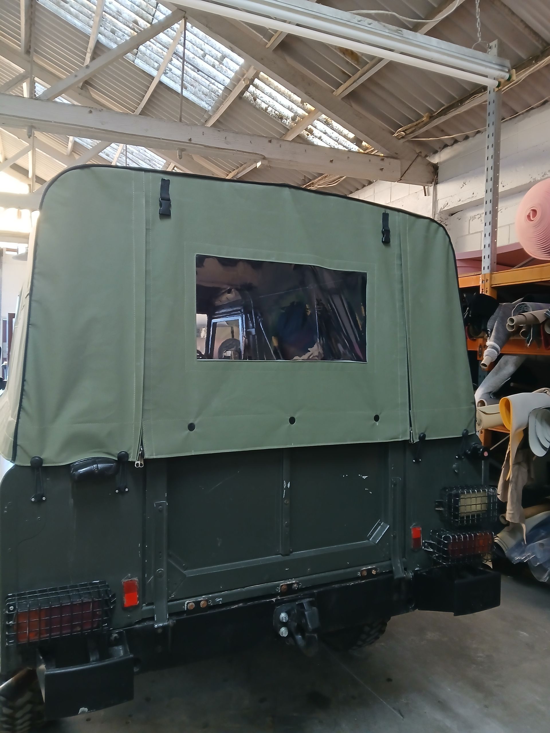 Gray sofa in front of a blue and white vintage car in a workshop.