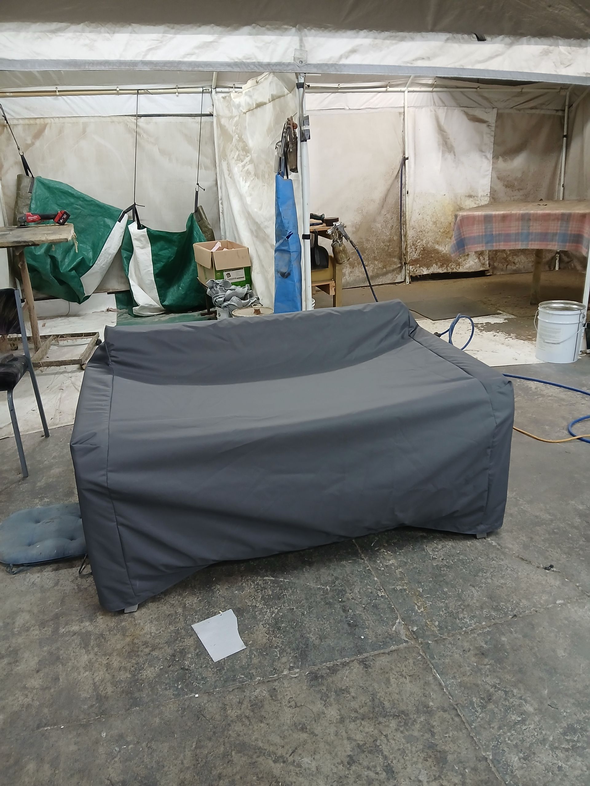 Dark gray covered outdoor sofa in a workshop setting.