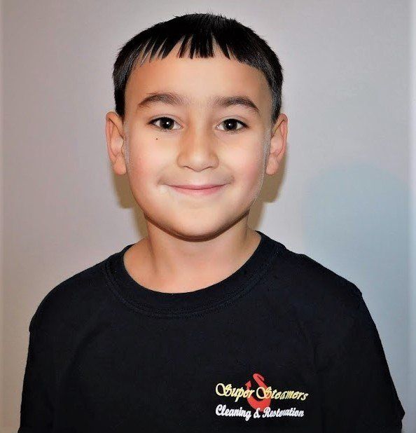 Boy in black shirt with short dark hair smiles. 
