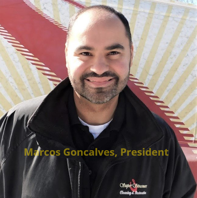 Man with a beard in a black jacket smiles at the camera, text reads “Marcos Goncalves, President”.
