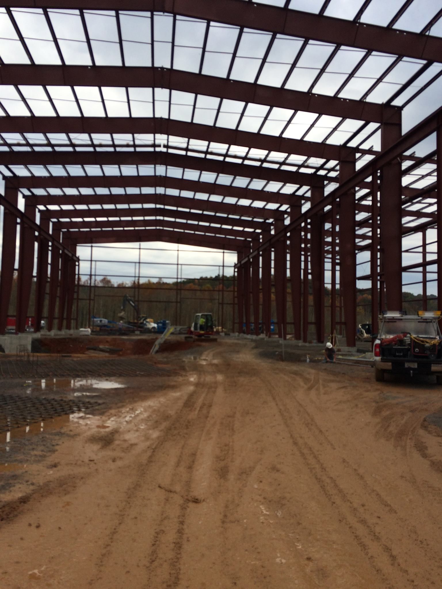 A large metal structure is being built on a dirt road.