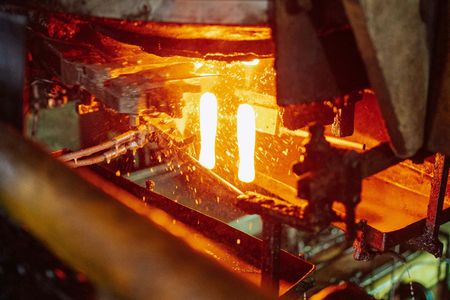 Glowing red-hot glass containers moving along an industrial manufacturing production line.