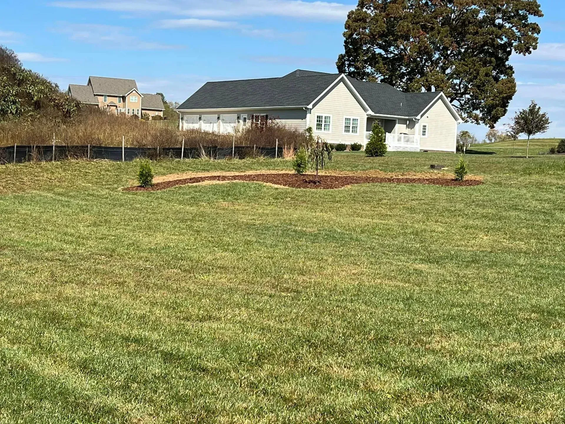 A large grassy field with a house in the background.