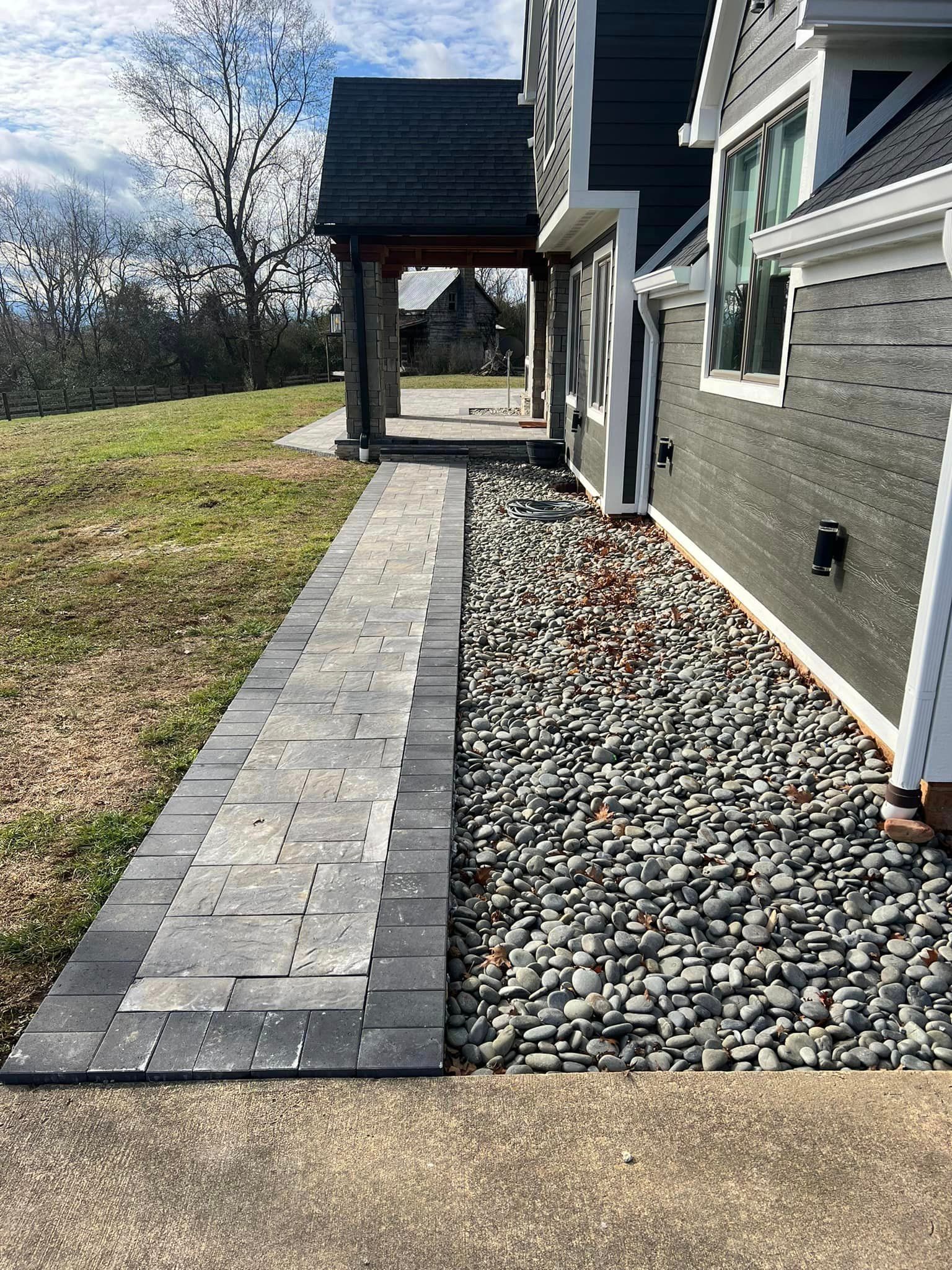 A walkway leading to a house with rocks on the side of it.