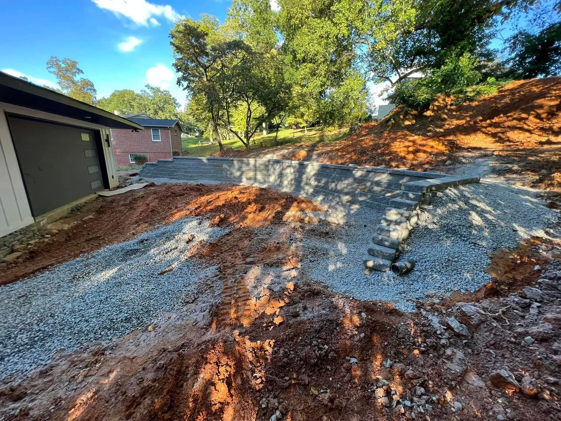 A dirt road leading to a garage with a house in the background.