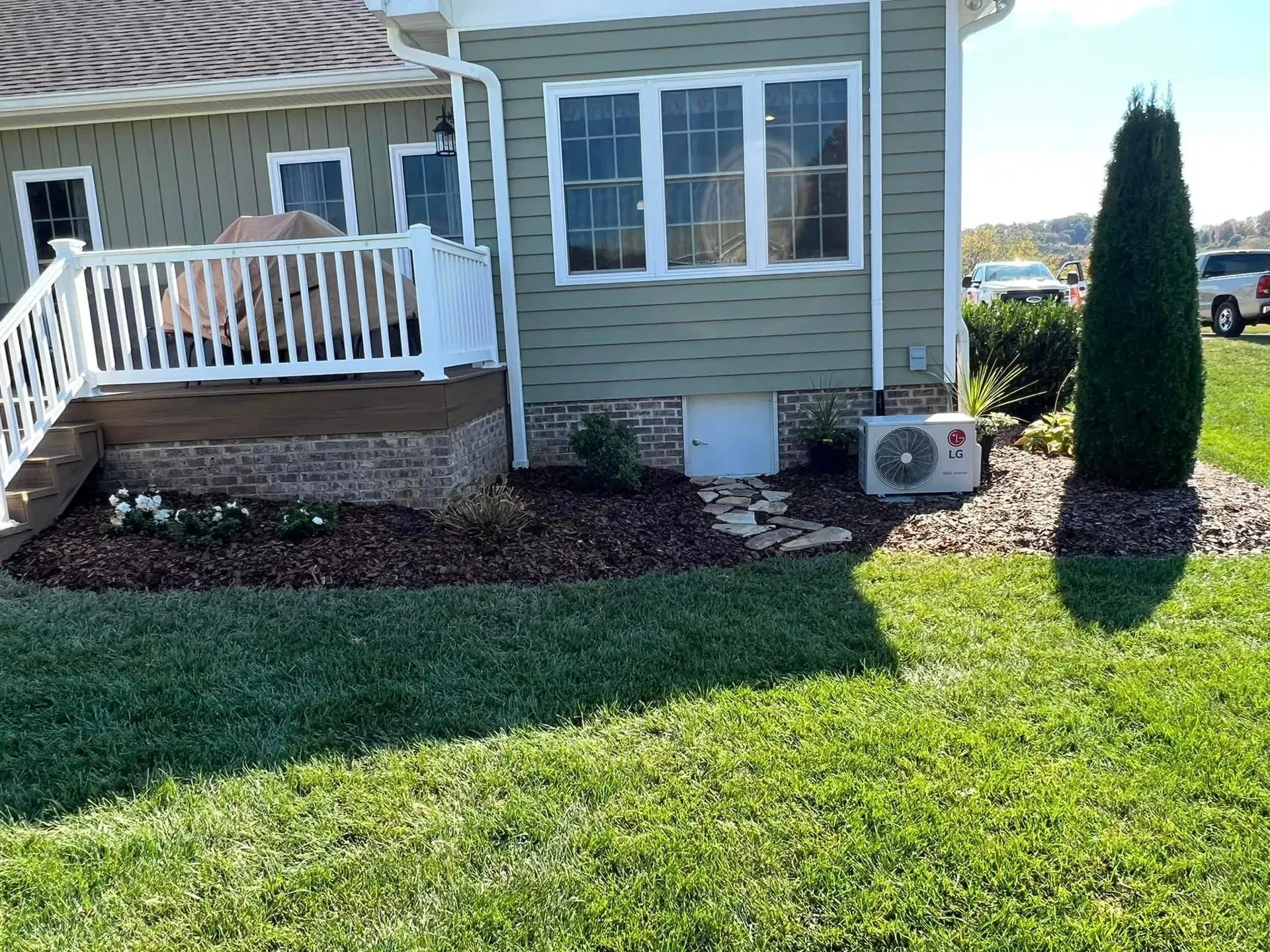 A house with a deck and stairs is sitting on top of a lush green lawn.