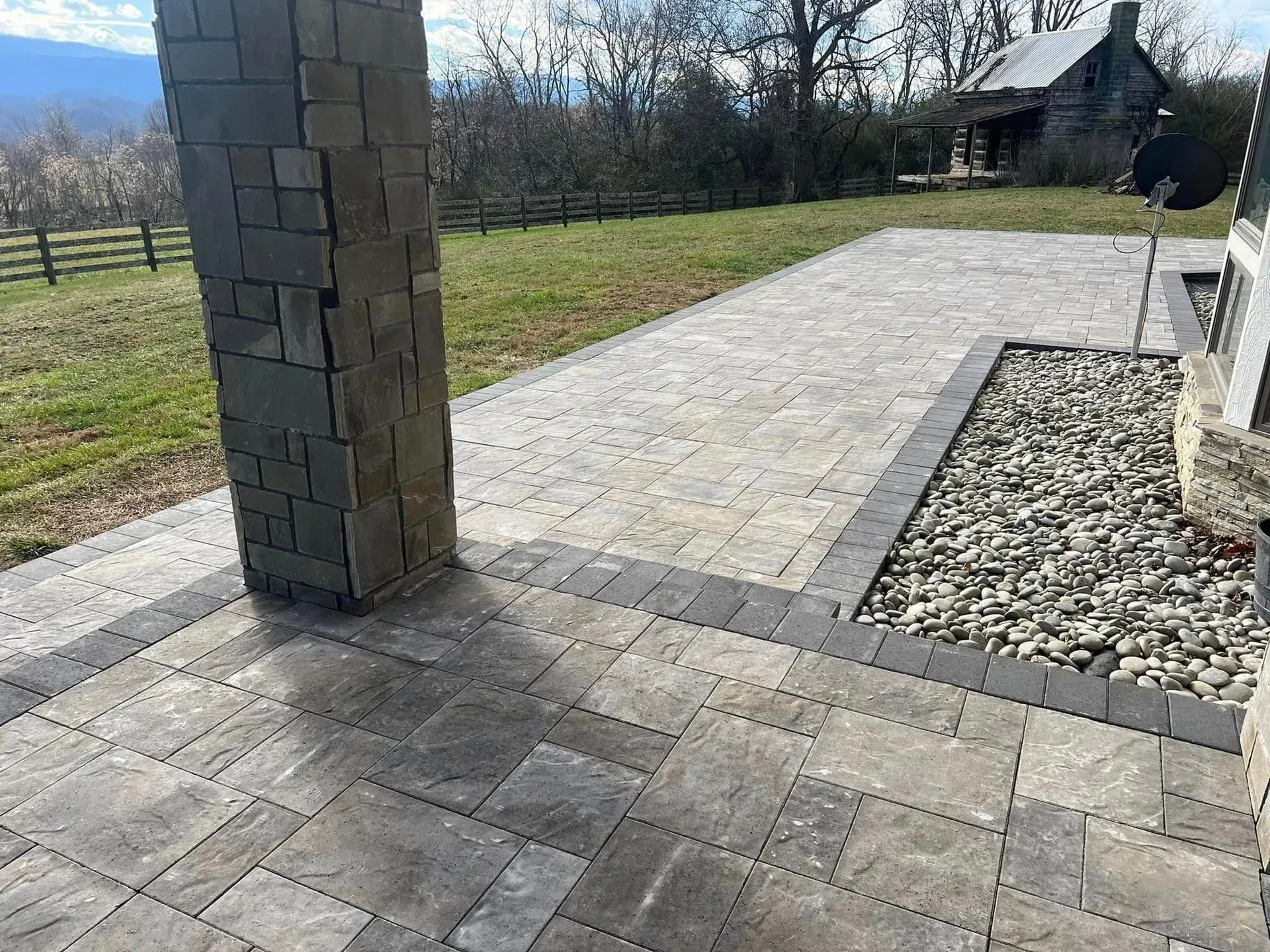 A patio with a chimney in the middle of it and a house in the background.
