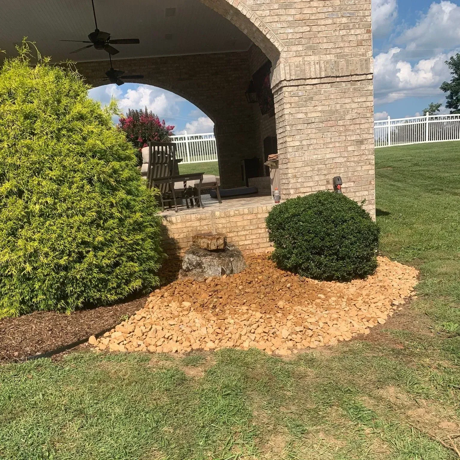 A brick building with a patio and a few bushes in front of it.