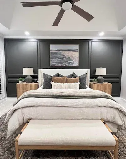 A modern bedroom with a bed, artwork, two nightstands, and dark gray paneled wall.
