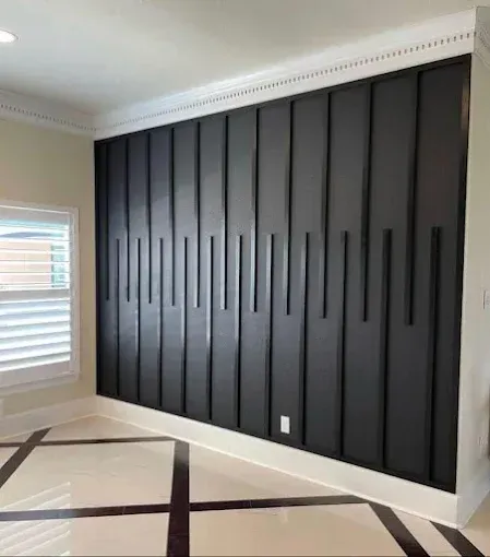 Black panel accent wall with vertical and horizontal lines, white crown molding and floor trim.