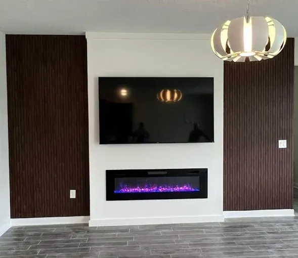 Living room with TV above a fireplace flanked by vertical wood paneling.