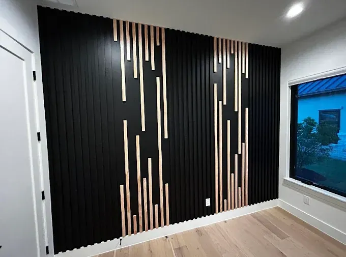 Black accent wall with vertical wooden strips and light wood accents in a room with a window and white door.