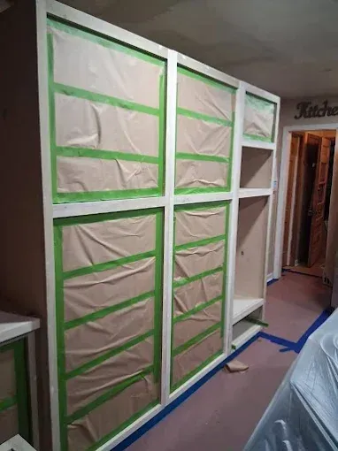 Kitchen cabinets masked with paper and green tape, ready for painting.
