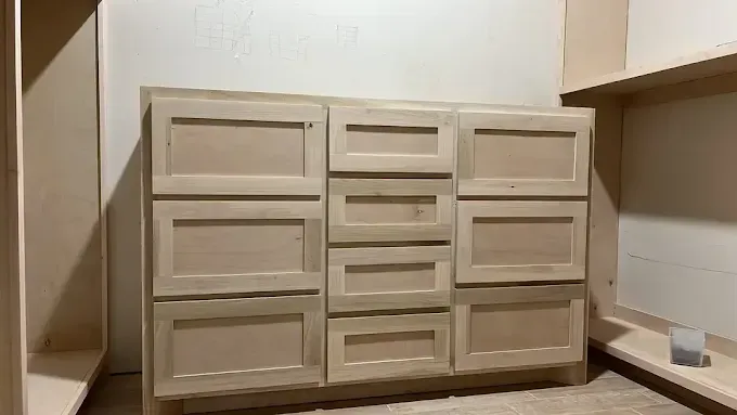 Wooden cabinet with multiple doors and drawers built into a wall.